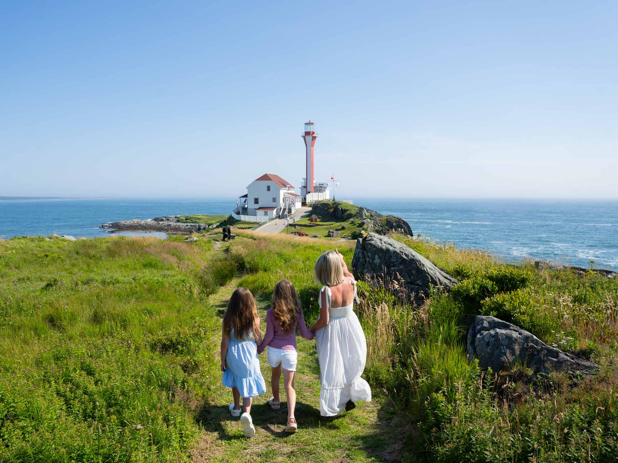 A family exploring the grounds at Cape Forchu Lighthouse near Yarmouth, Nova Scotia, on a warm, sunny summer day.