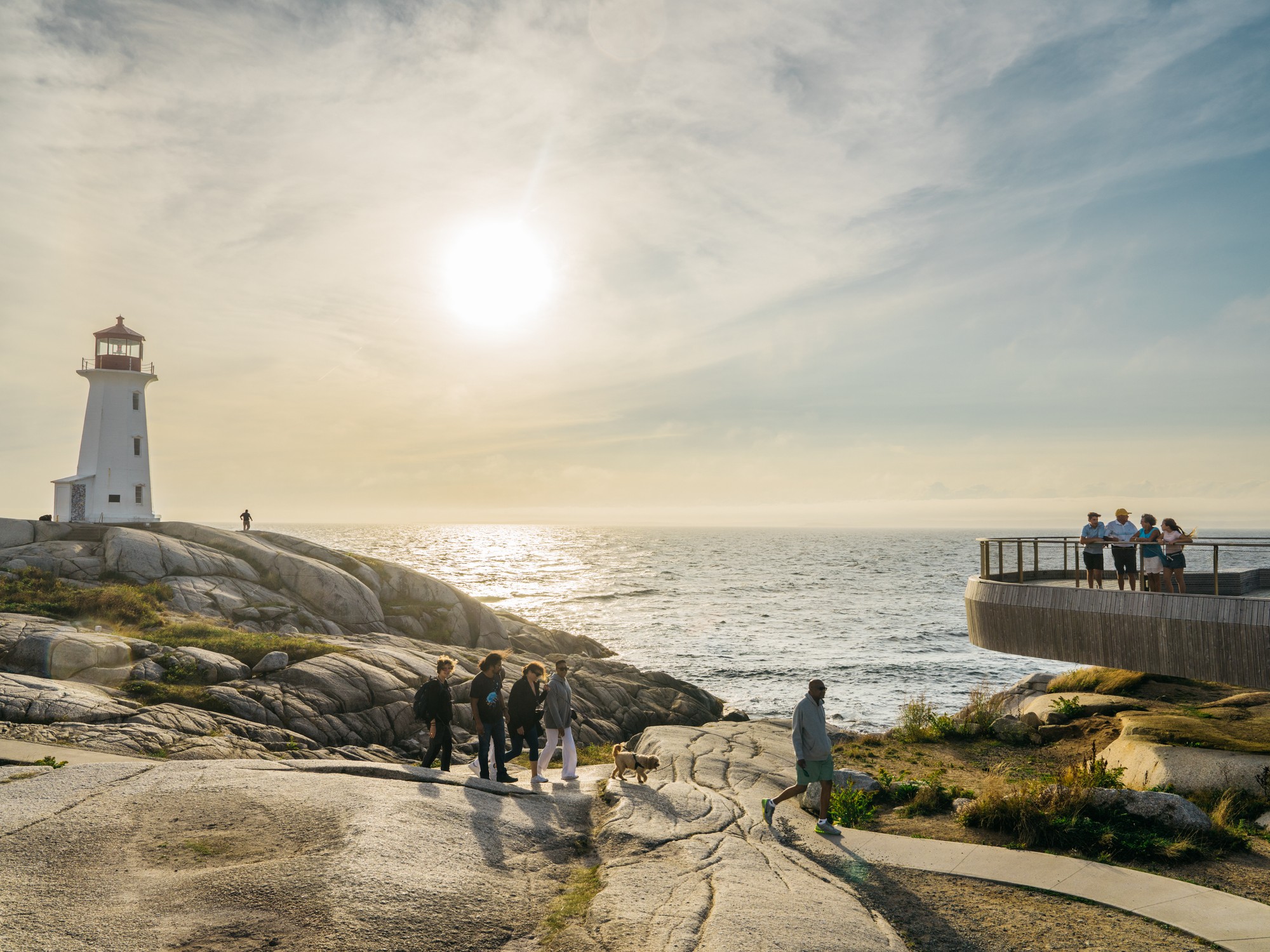 People view the Peggy's Cove Lighthouse in Nova Scotia during sunset