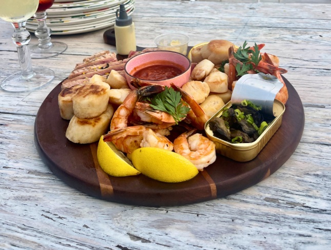A seacuterie board featuring shrimp, scallots and fish.