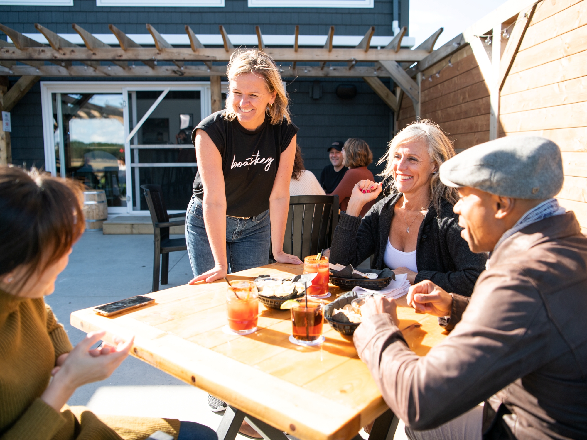 Server talking to a table of people enjoying beer on a sunny patio