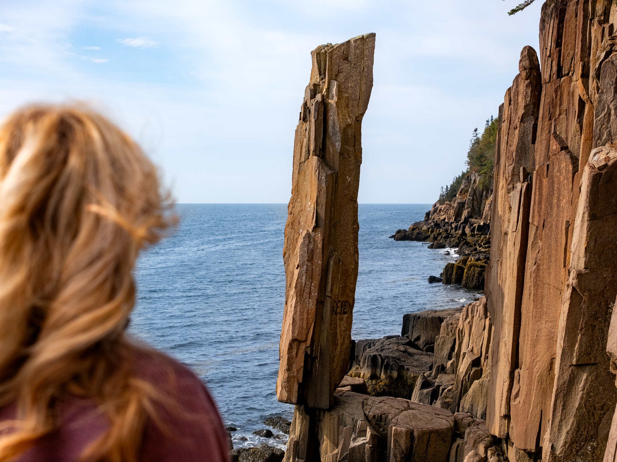 A woman observes the Balancing Rock near Digby, Nova Scotia