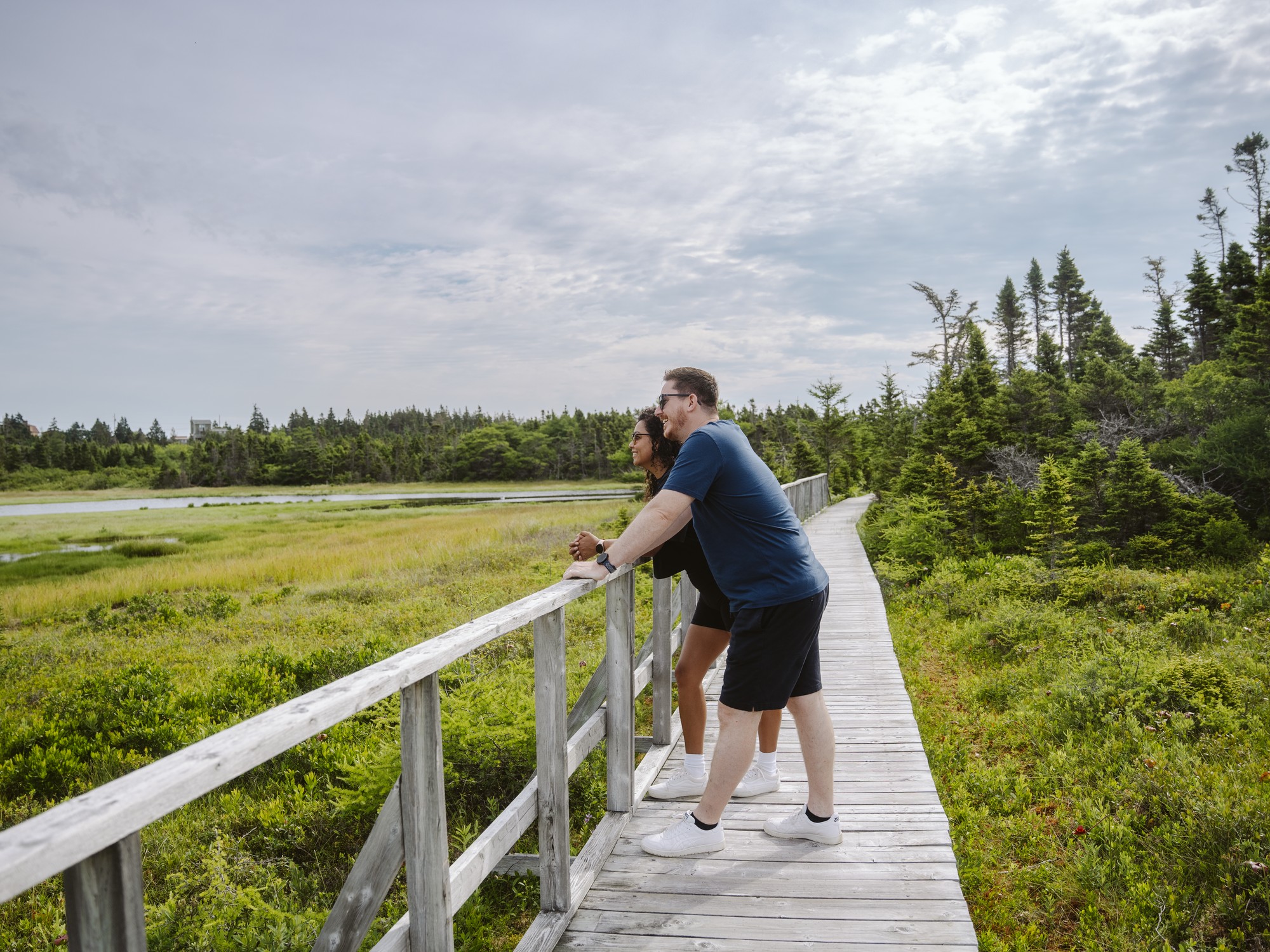 Two people look out at the marsh while hiking on Chapel Gully Trail in Nova Scotia