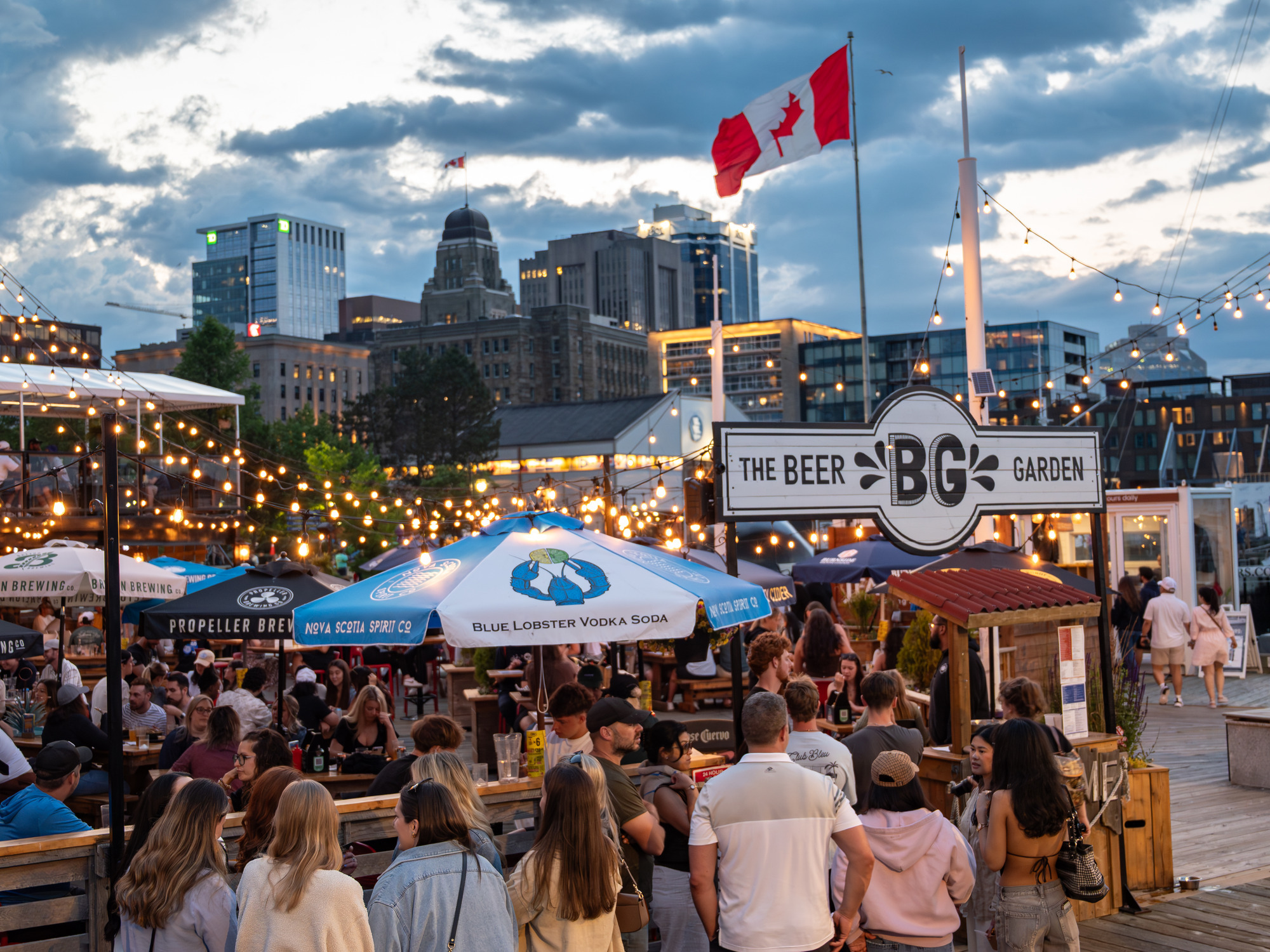 Lively shot of the Beer Garden on the Halifax Waterfront with a Canadian flag in the background