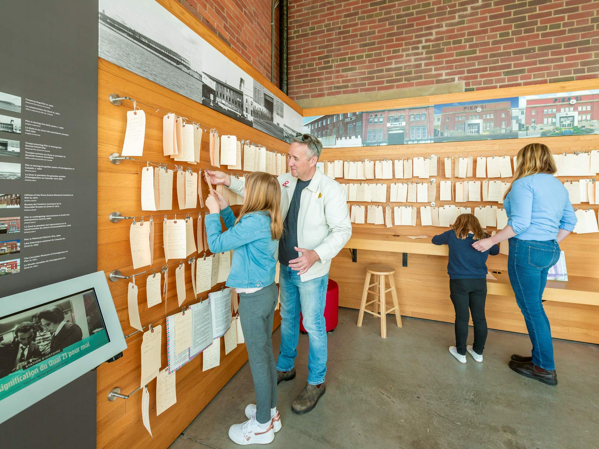 Visitors look at a wall of tags and exhibit at the Canadian Museum of Immigration at Pier 21