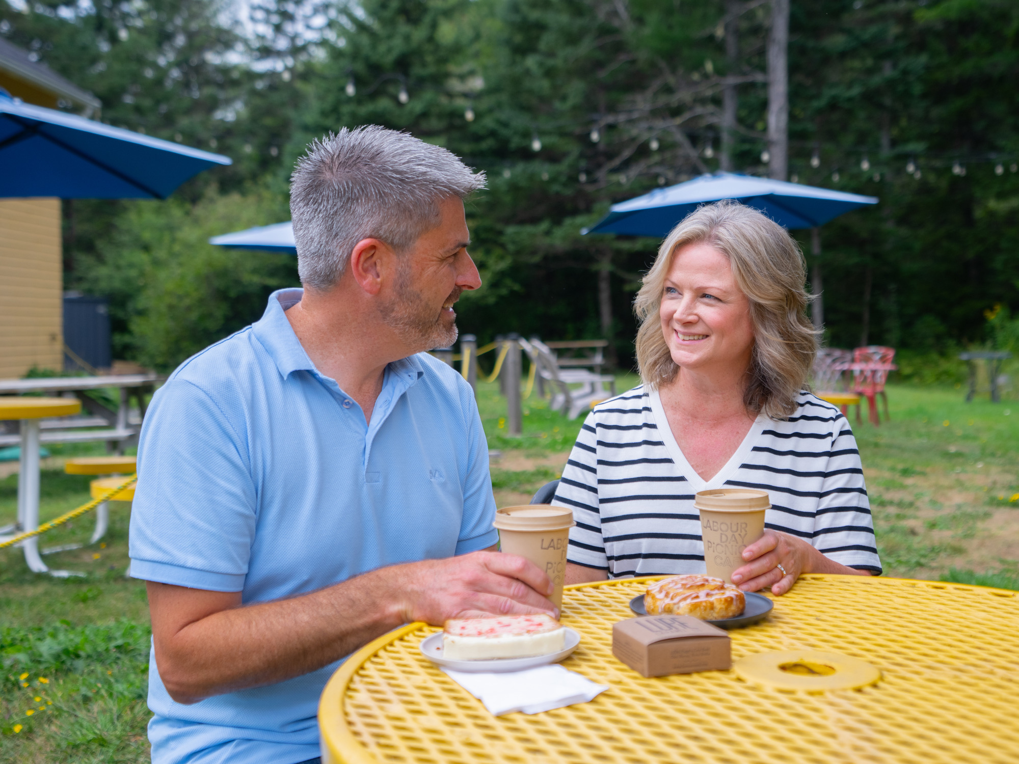Couple enjoying a coffee and treats on a picnic table
