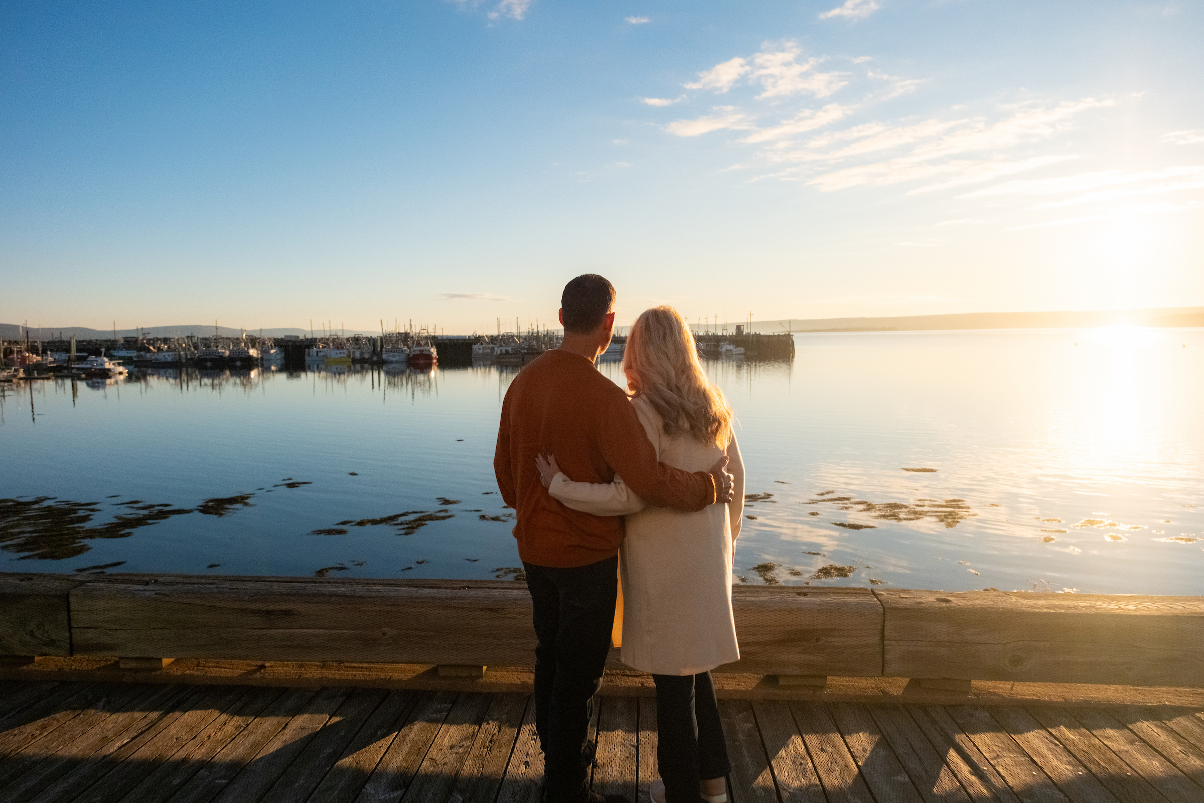 A couple overlooks Digby's wharf and scallop fishing fleet at sunset