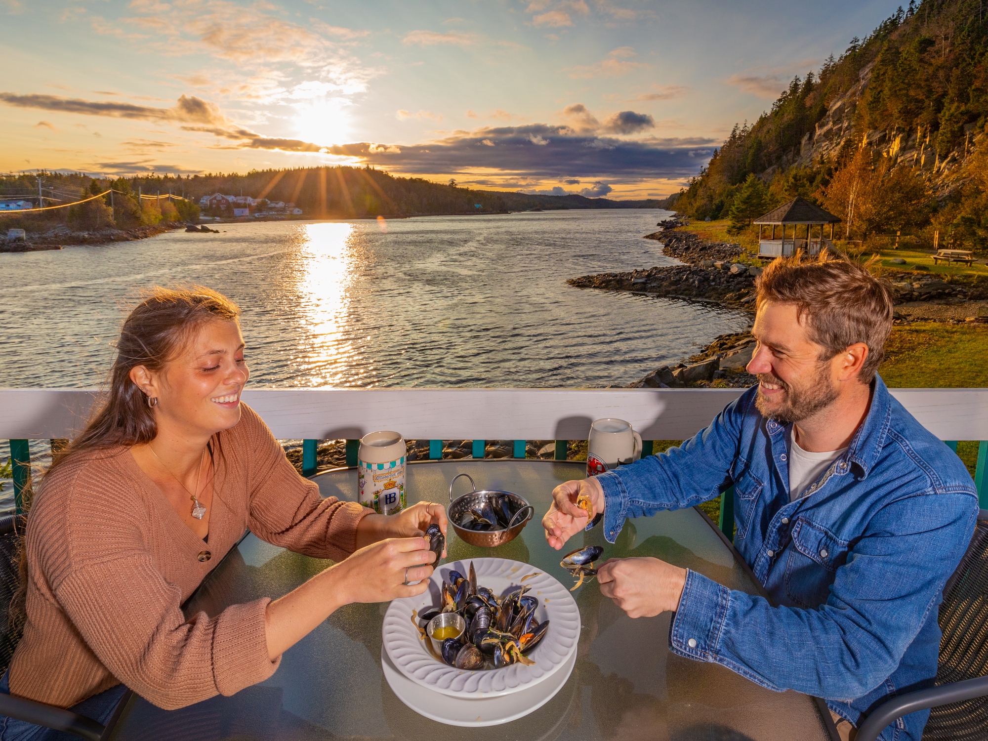 People enjoying a plate of mussels on a patio over the ocean