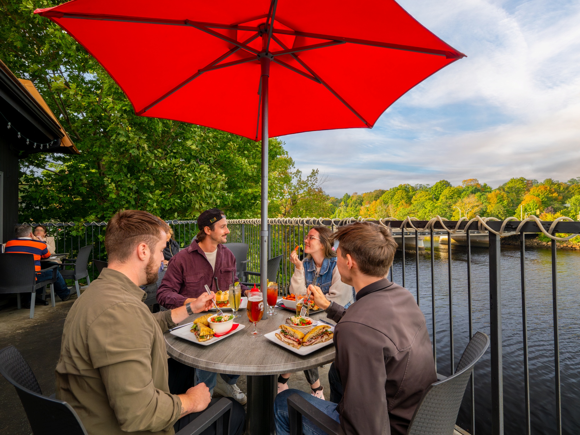 People enjoying a meal on a patio beside the water