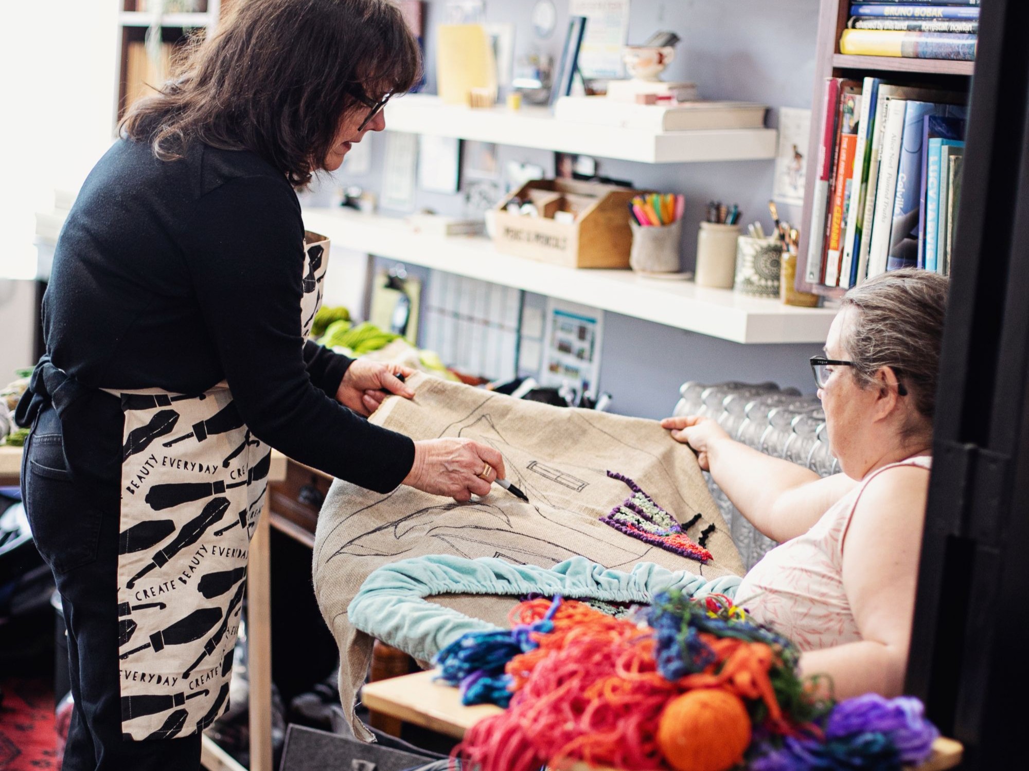 Artist Deanne Fitzpatrick guides a rug hooking student