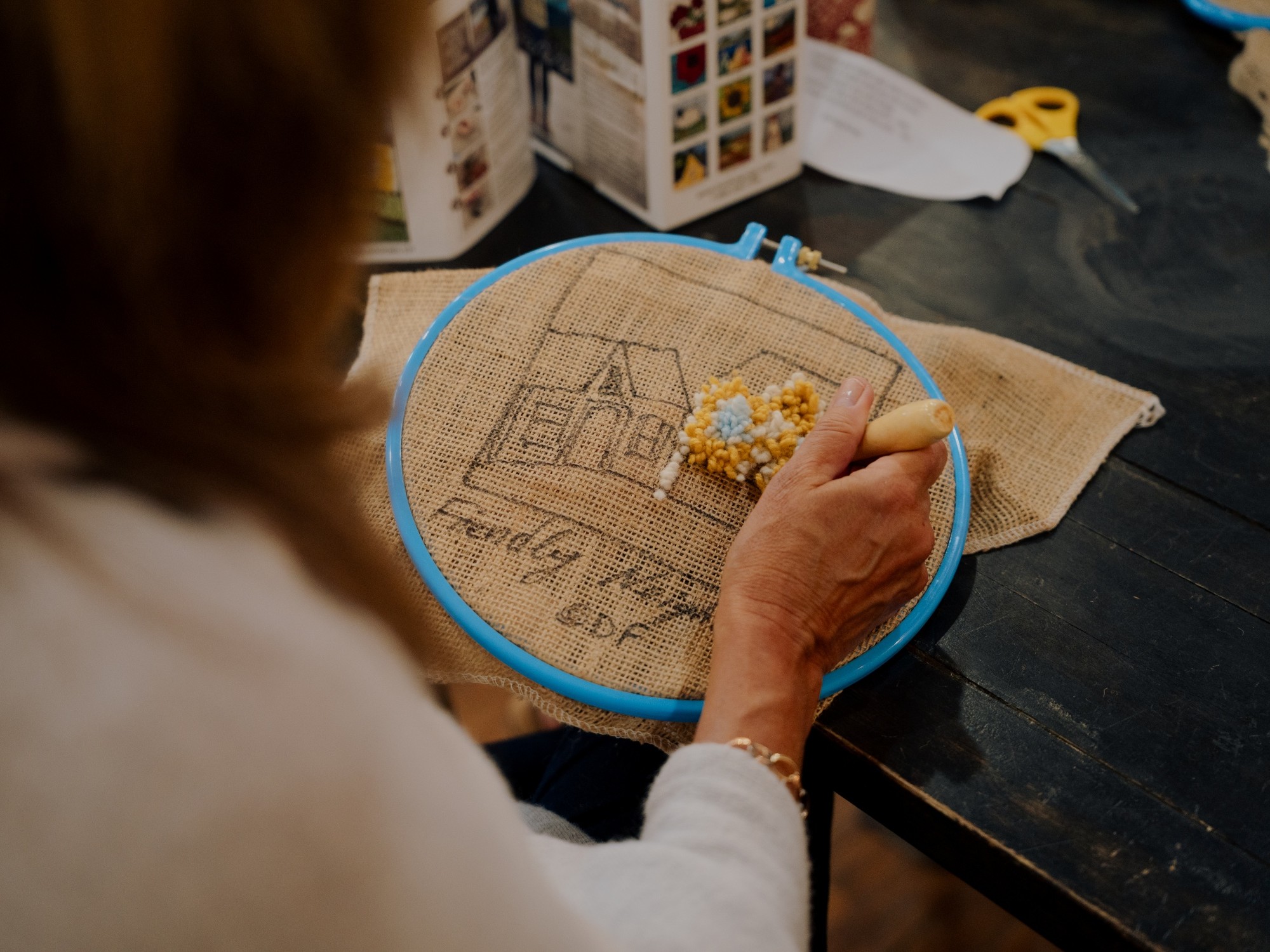 A woman rug hooking at Deanne Fitzpatrick Rug Hooking Studio