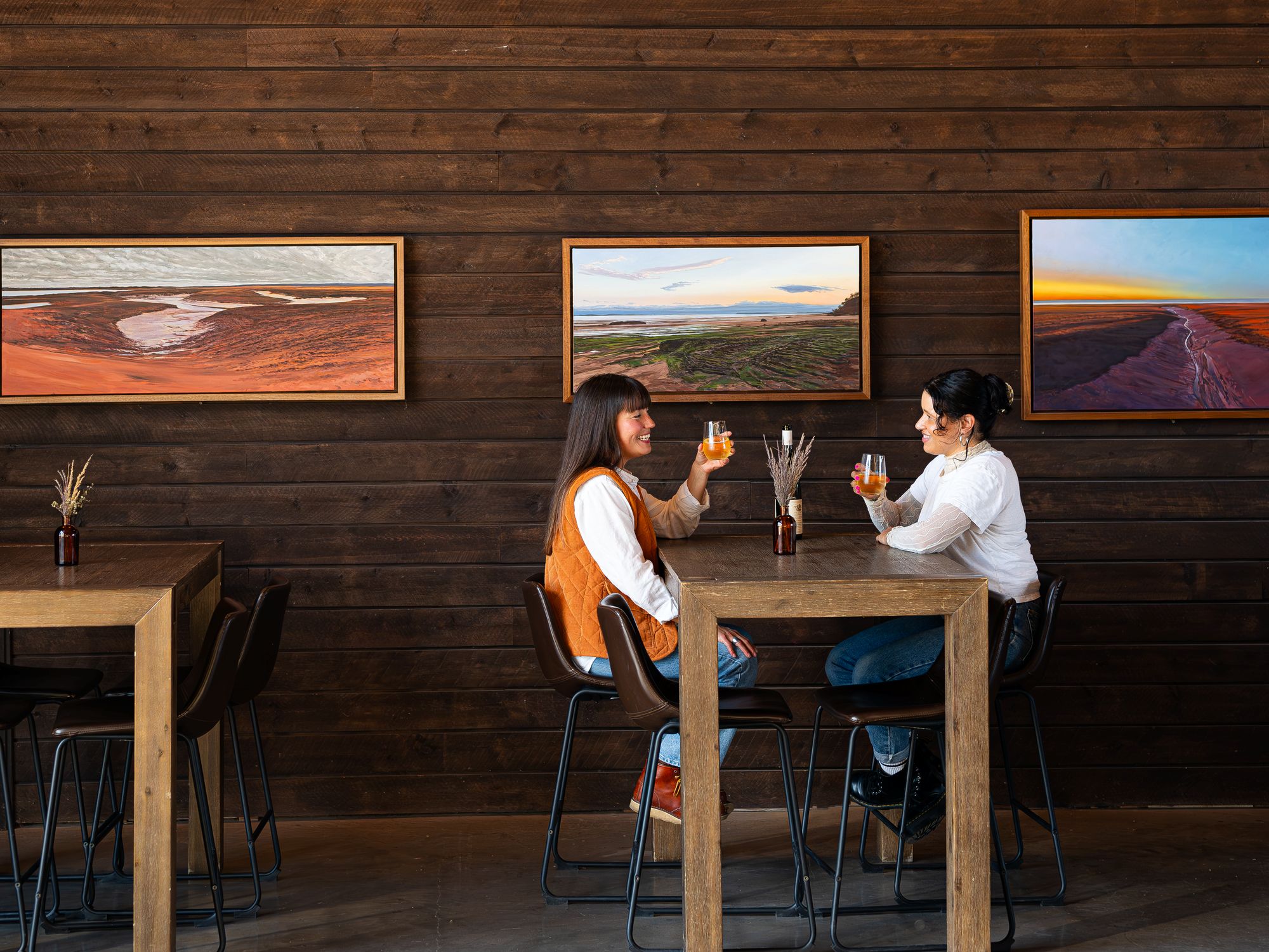 Two women enjoying a glass of wine at a high top table at Lightfoot & Wolfville Vineyards