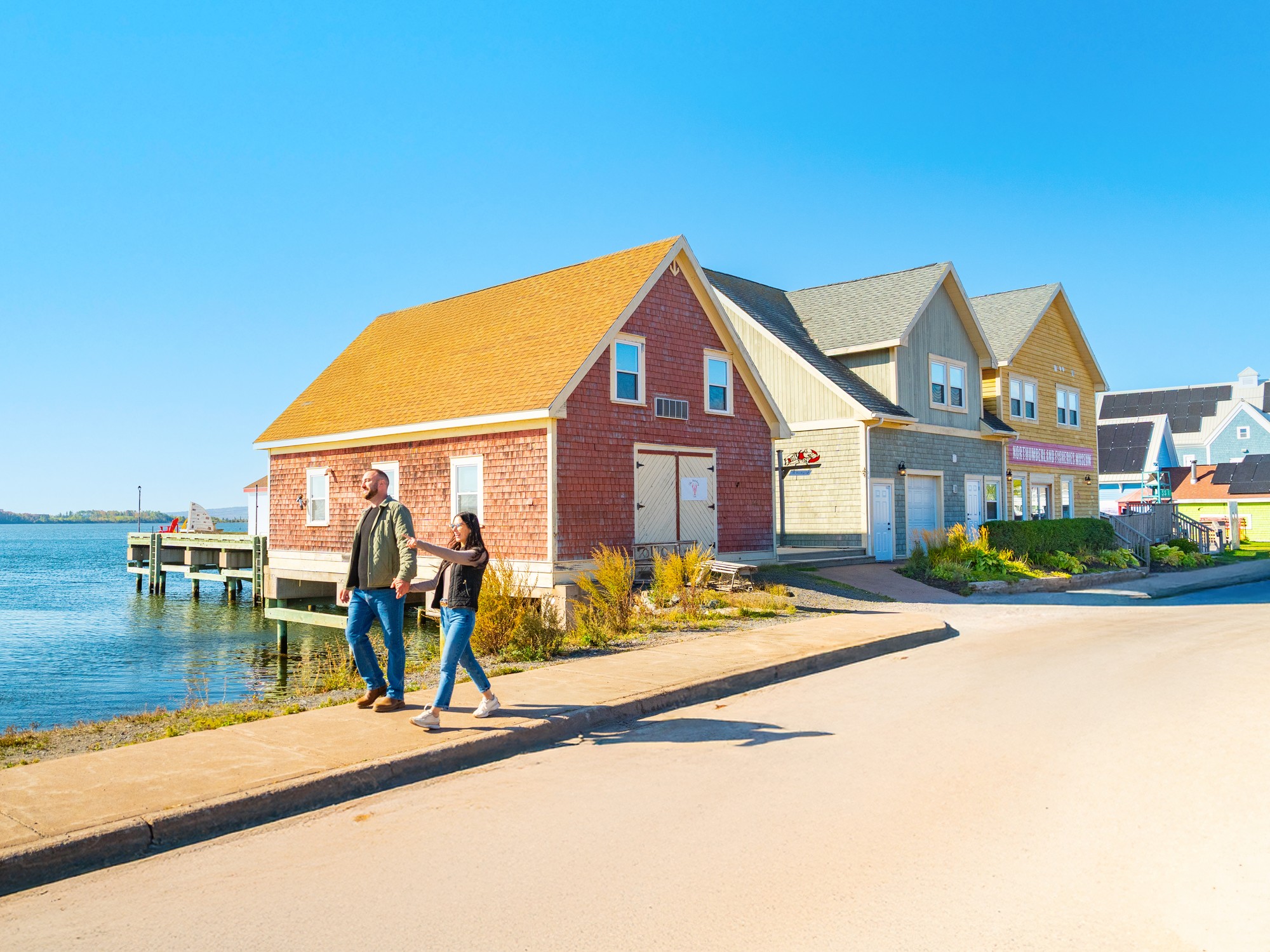 Two people walk on the Pictou Waterfront in Nova Scotia during fall