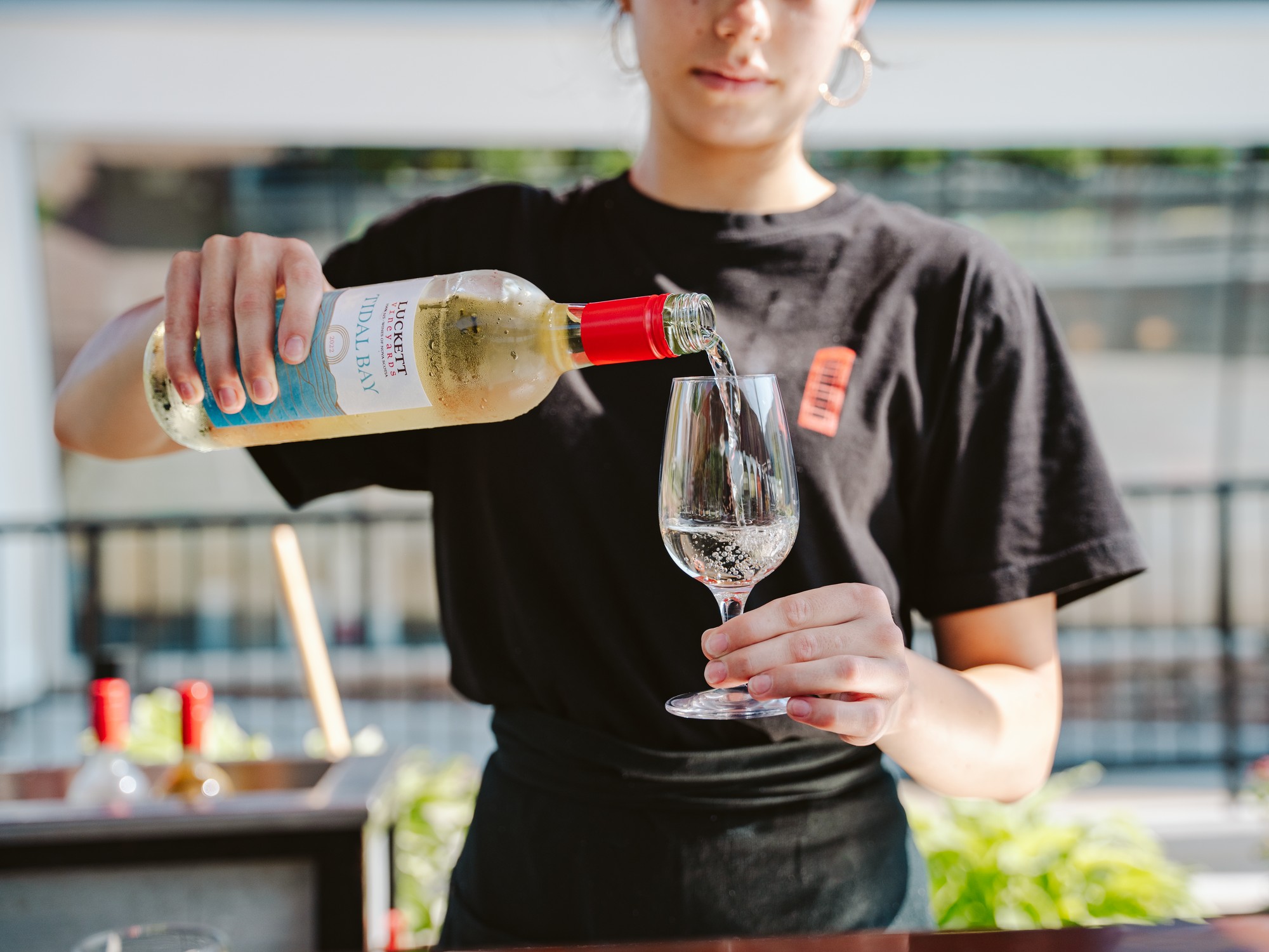 A woman pours Tidal Bay wine into a glass at Luckett Vineyards in Nova Scotia