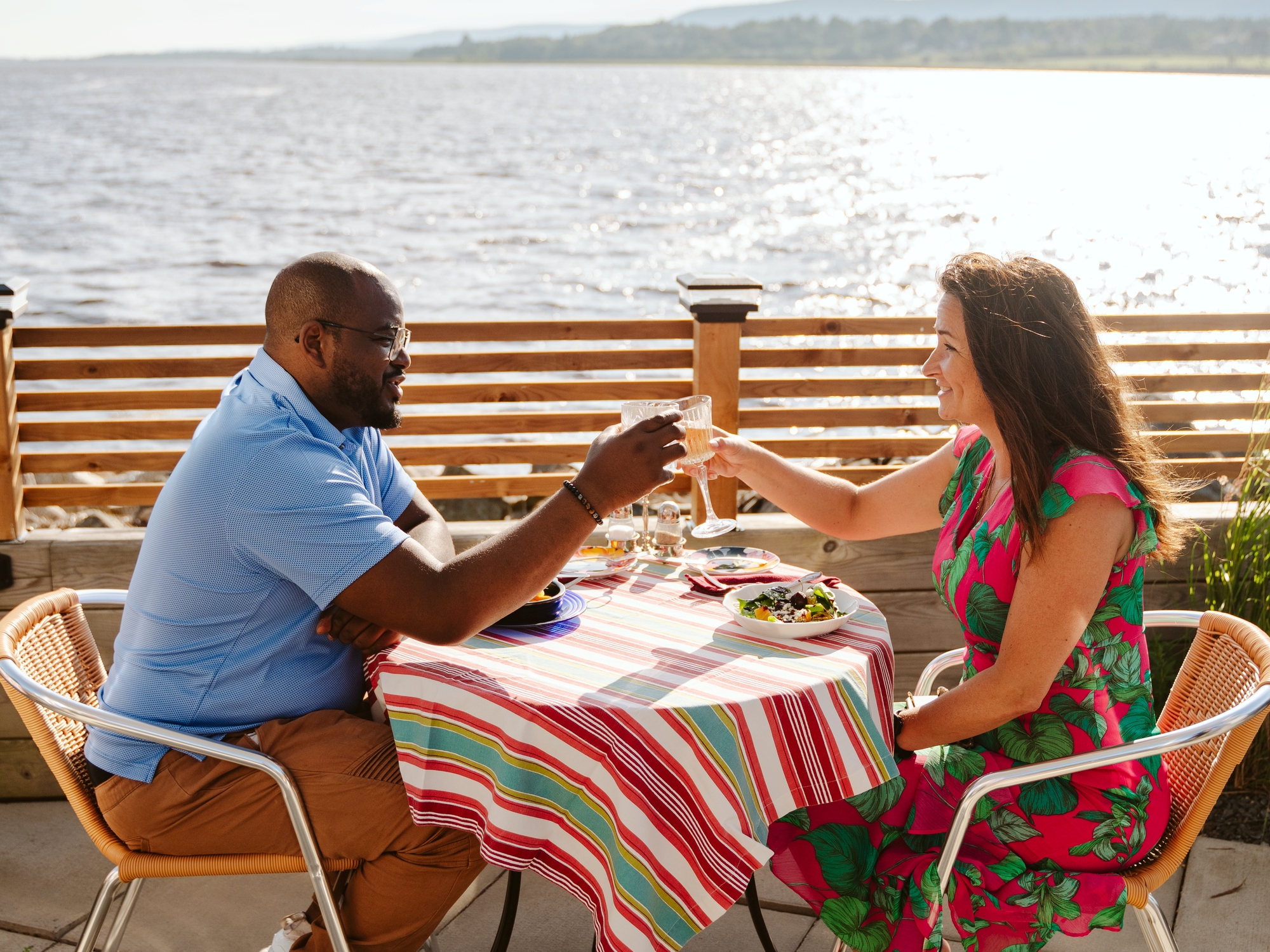 Couple cheersing on a patio by the water