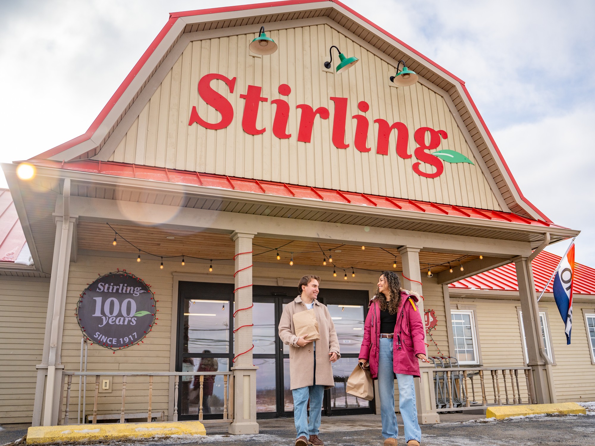 Two people in front of the exterior of Stirlings Farmers Market in Wolfville, Nova Scotia