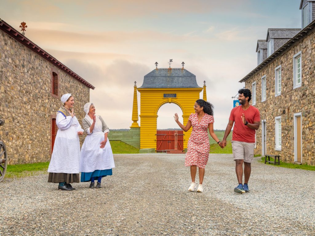 A couple waves to costumed interpreters at Fortress of Louisbourg in Nova Scotia
