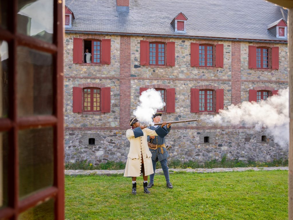 A woman shoots a musket at Fortress of Louisbourg in Nova Scotia