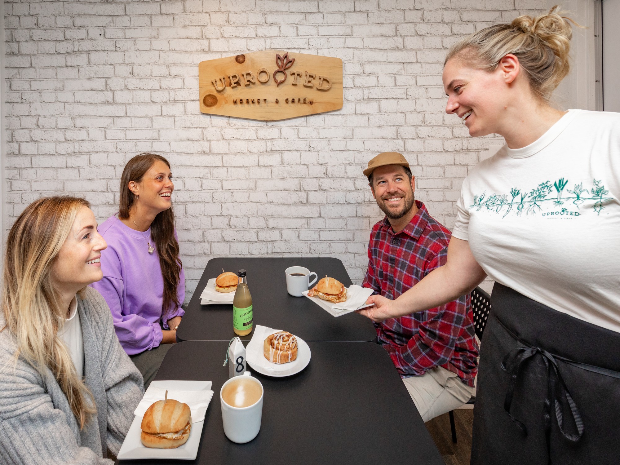 A server brings food to a table of guests at Uprooted Cafe in Nova Scotia